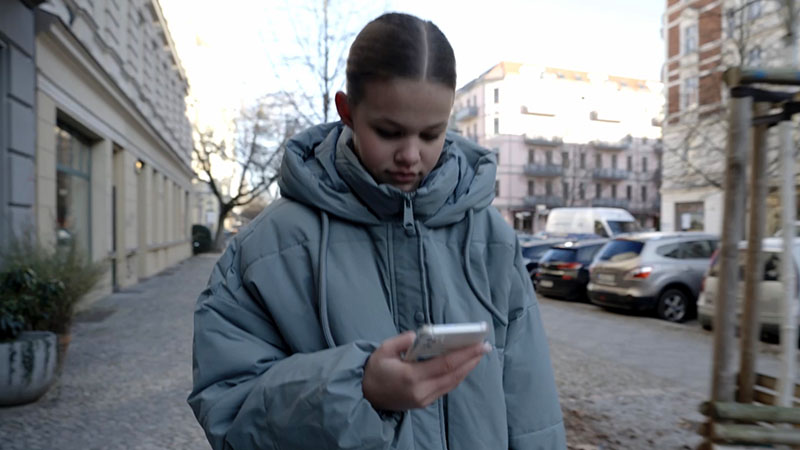 Ein Mädchen auf einer Straße schaut auf ein Smartphone Ein Mädchen auf einer Straße schaut auf ein Smartphone